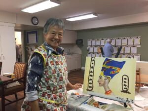 An elderly resident at Brookdale Retirement in Tomball, TX with her work. Houston artist Tasnuva Rahman gives back to the community by teaching an art class.